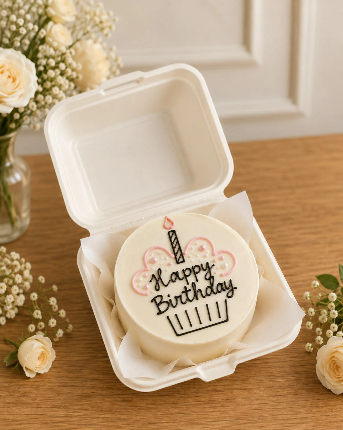 Ivory birthday bento cake in clamshell packaging featuring piped candle cupcake illustration and Happy Birthday text