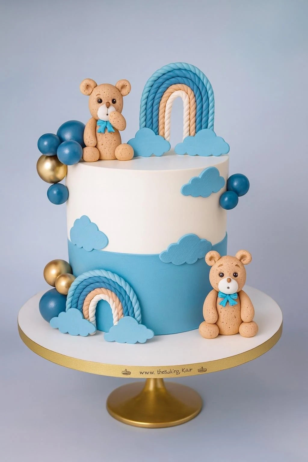 Children's birthday cake with teddy bears, rainbow, and balloons on a white stand.