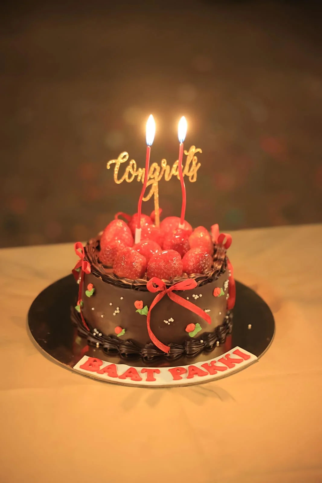 Chocolate cake with red berries and lit candles on a dark background