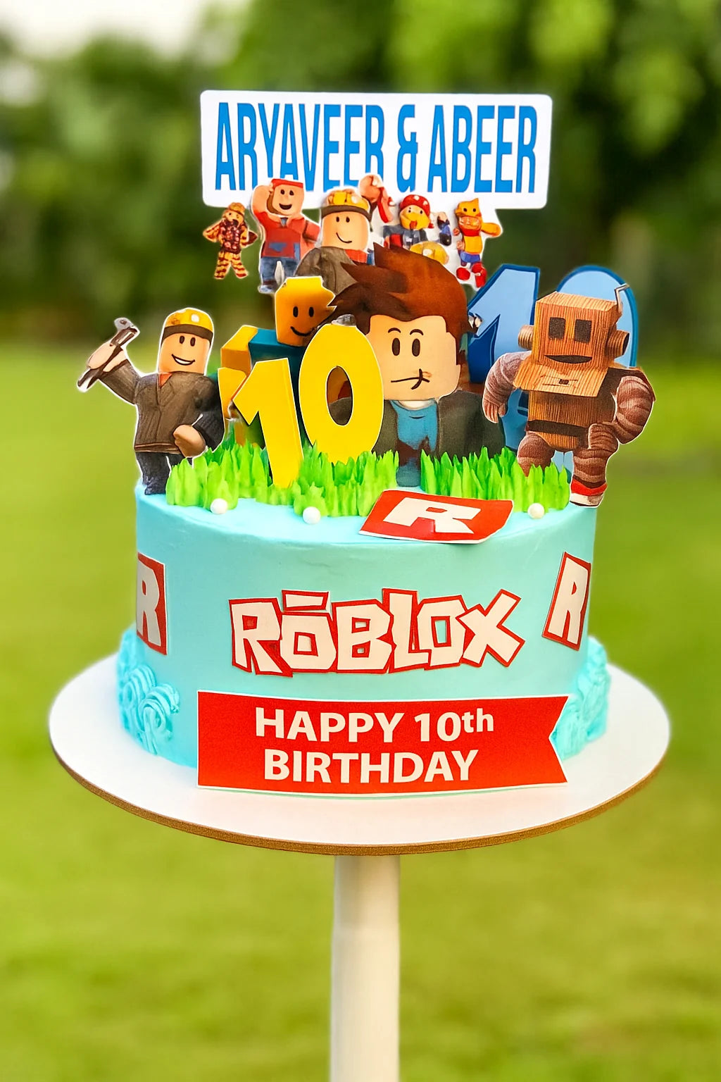 Roblox-themed birthday cake with characters and 'Happy 10th Birthday' text on a grassy background